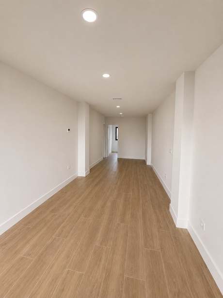 Salón-comedor diáfano de la vivienda Bajo E, de dos dormitorios, con suelo de madera clara.